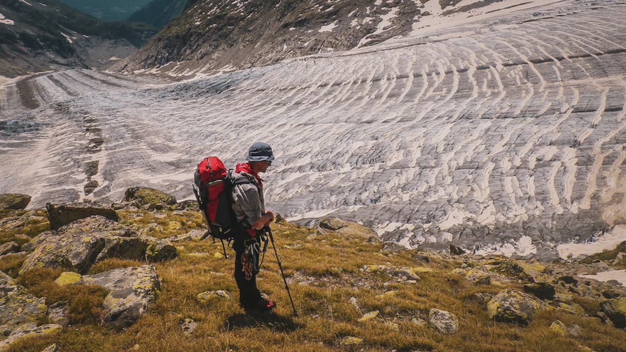 Randonneur contemplant le majestueux glacier d'Aletsch, entouré de paysages alpins spectaculaires.