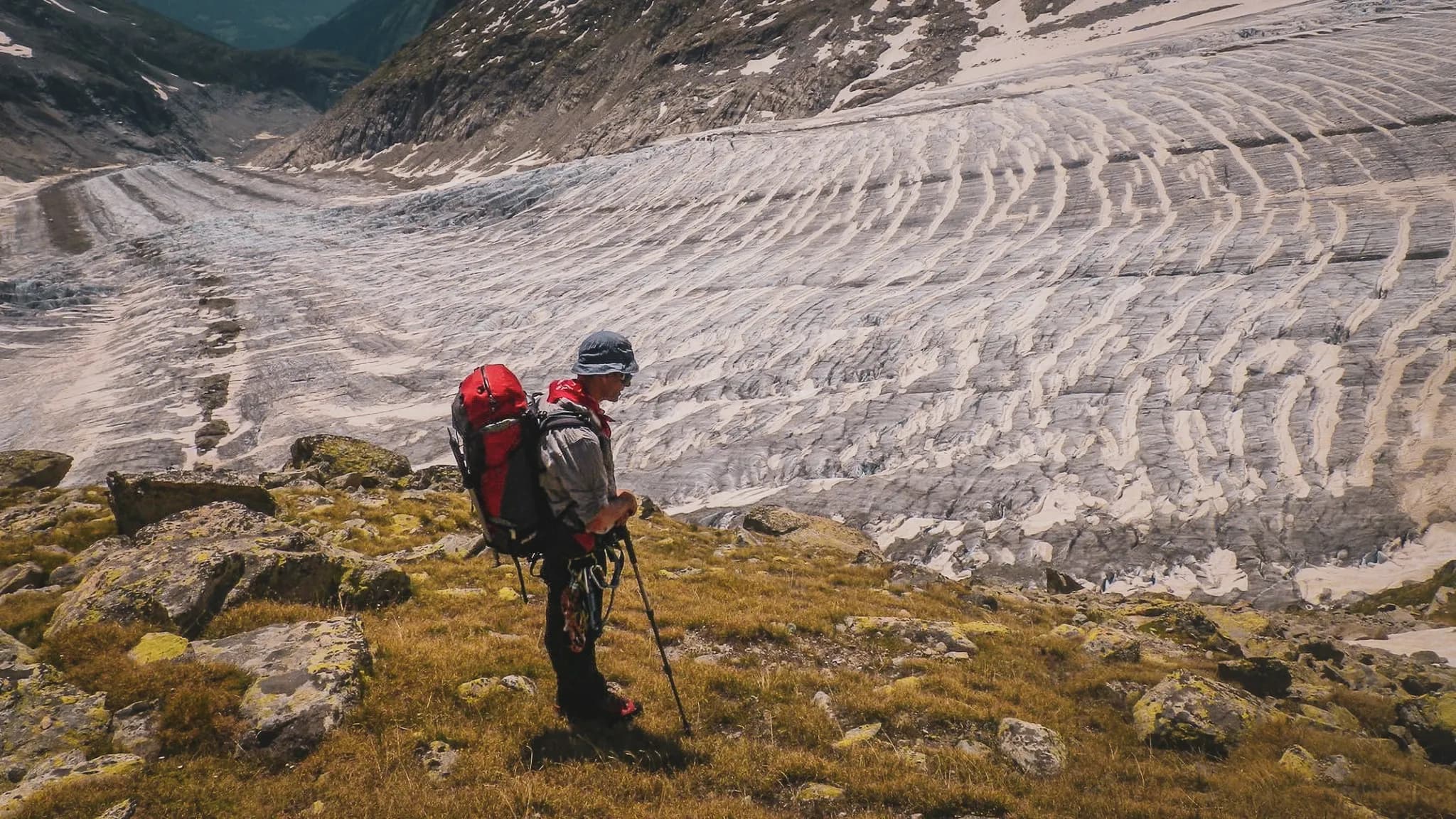 Randonneur contemplant le majestueux glacier d'Aletsch, entouré de paysages alpins spectaculaires.