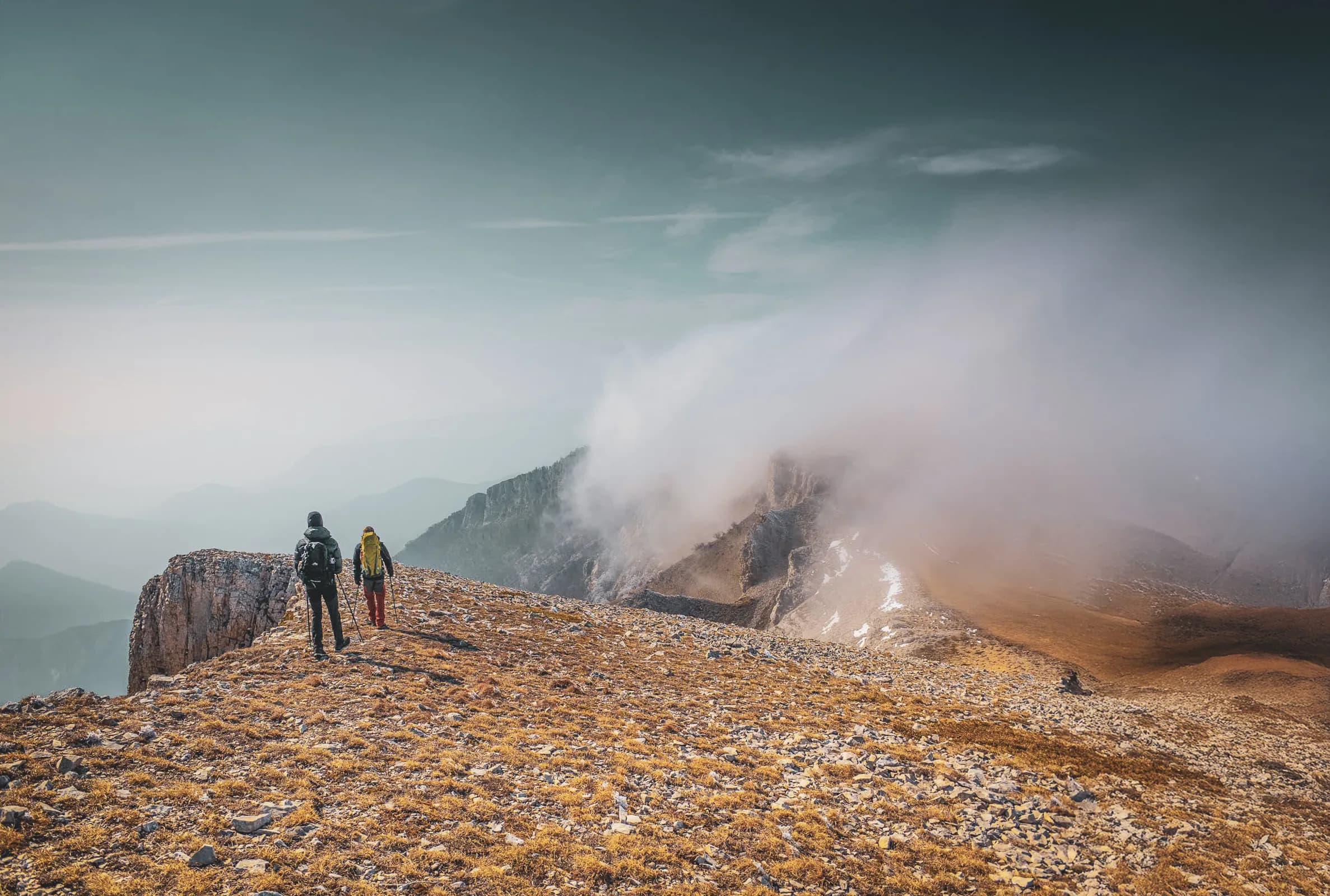 Two hikers on a steep path, exploring the majestic Vercors mountains.