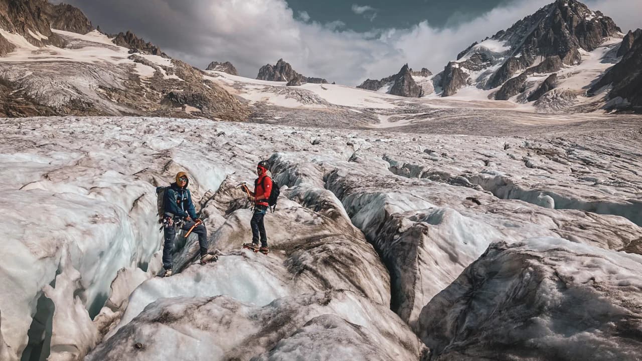 Deux alpinistes explorent un glacier majestueux sous un ciel dramatique à Chamonix.