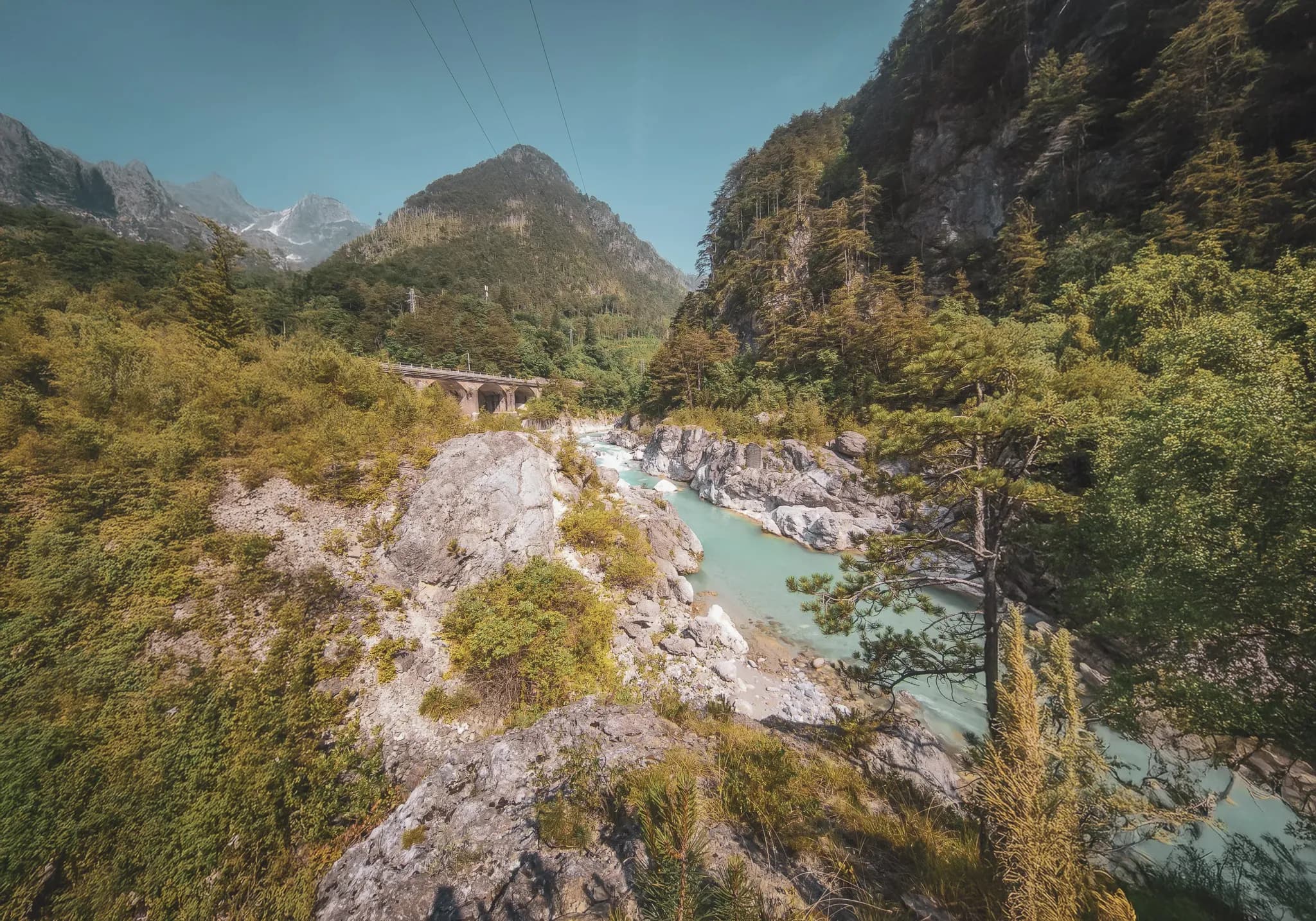 A turquoise river meandering between lush green mountains, ideal for packraft adventures.