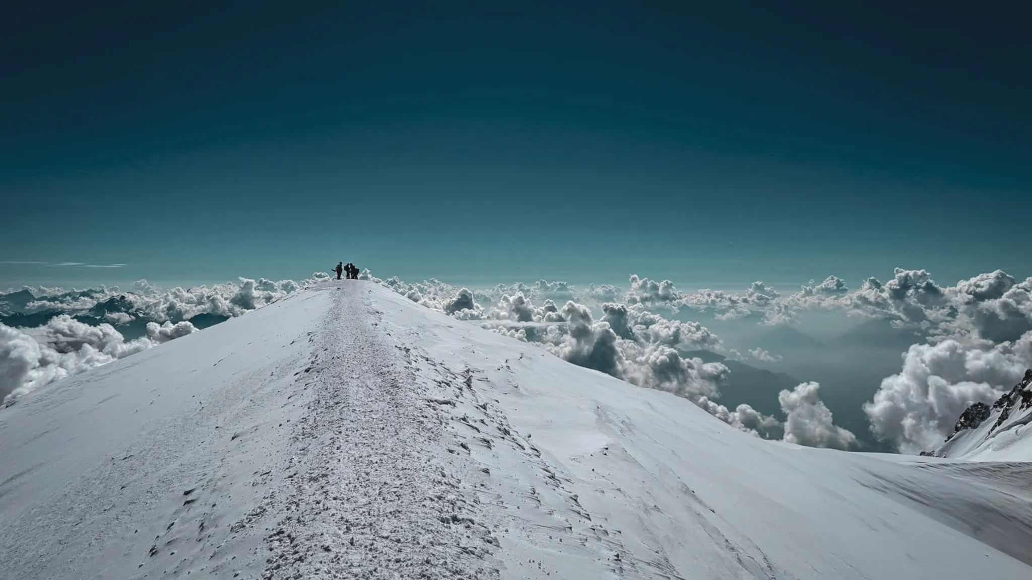 Sommet enneigé du Mont Blanc, surplombant des nuages, une aventure majestueuse attend.