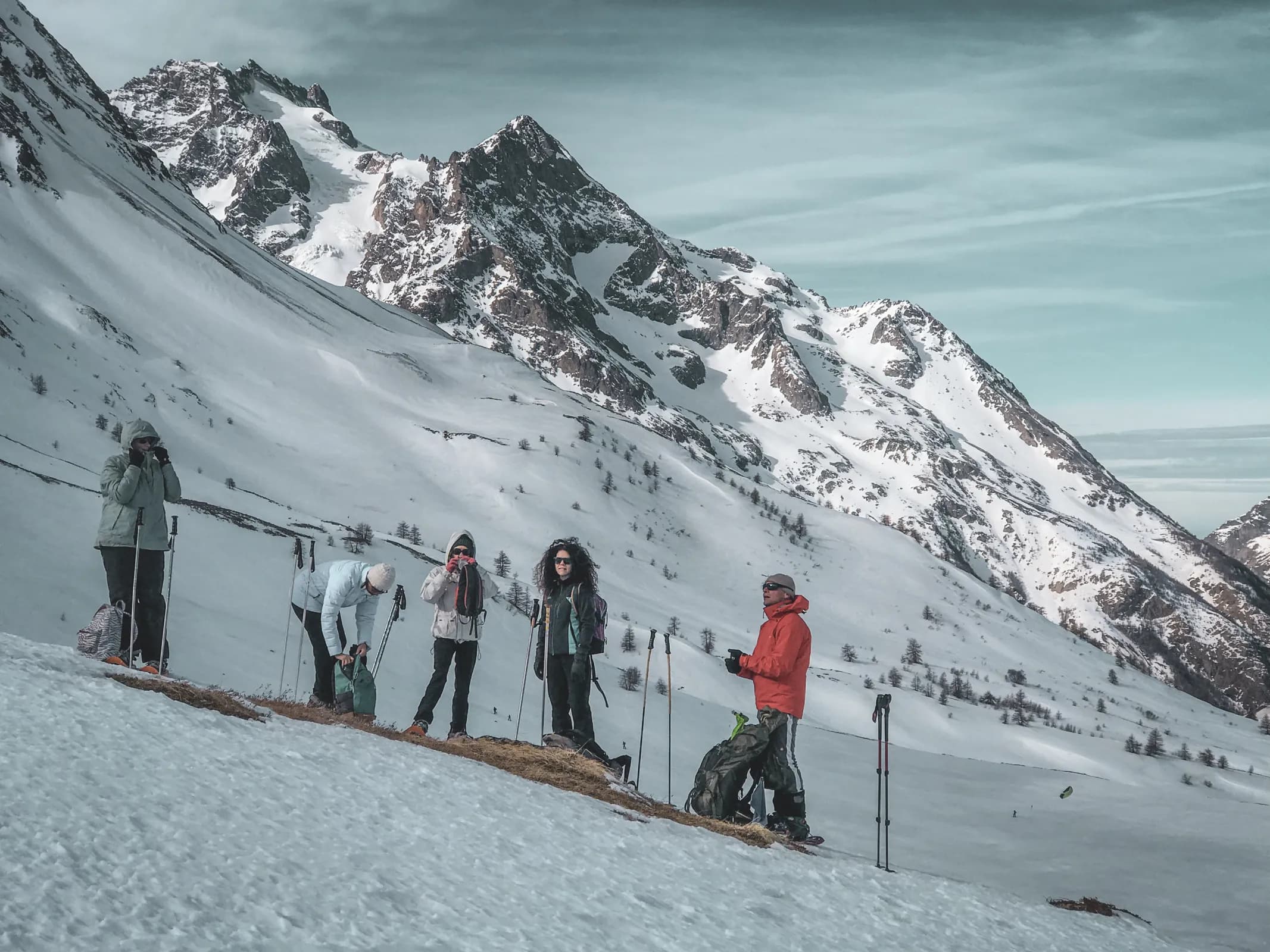 Groupe en randonnée raquette face aux majestueux glaciers des Écrins, paysages enneigés enchanteurs.