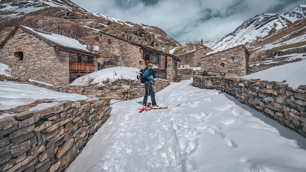 Touring skier in a mountain village, surrounded by snow and majestic Alpine scenery.