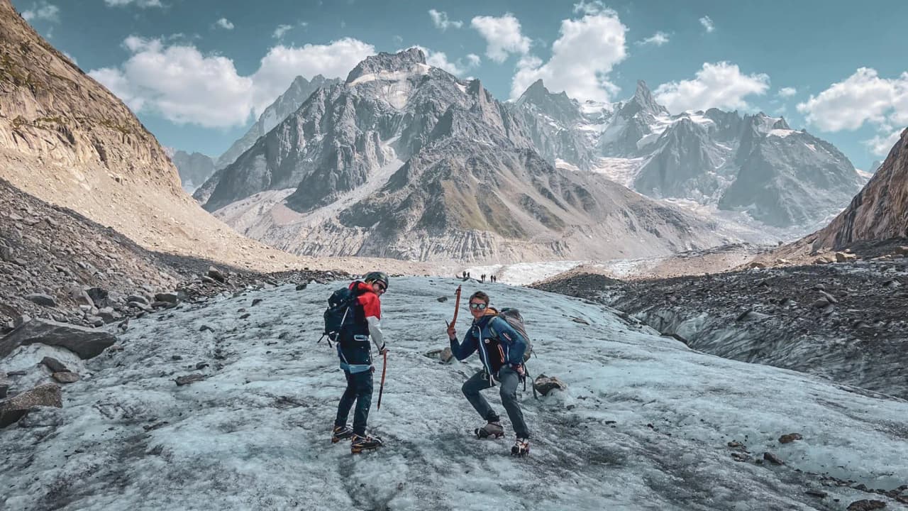 Deux alpinistes sur un glacier à Chamonix, avec des montagnes majestueuses en arrière-plan.