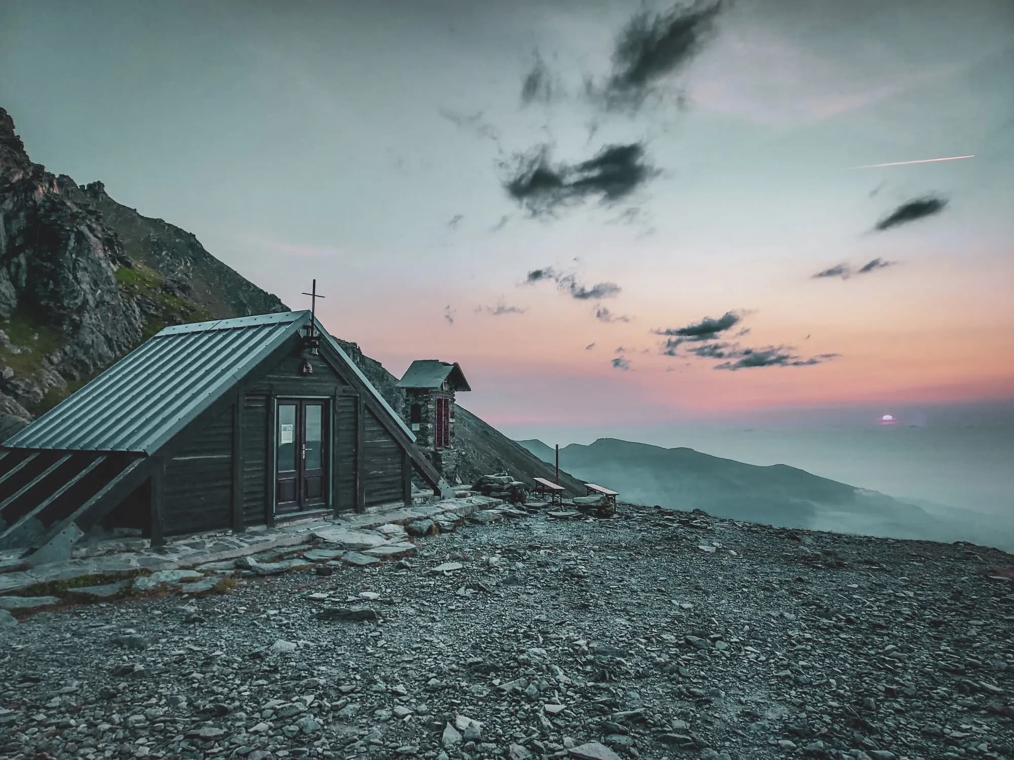 Refuge montagnard au coucher de soleil, entouré de paysages alpins à couper le souffle.