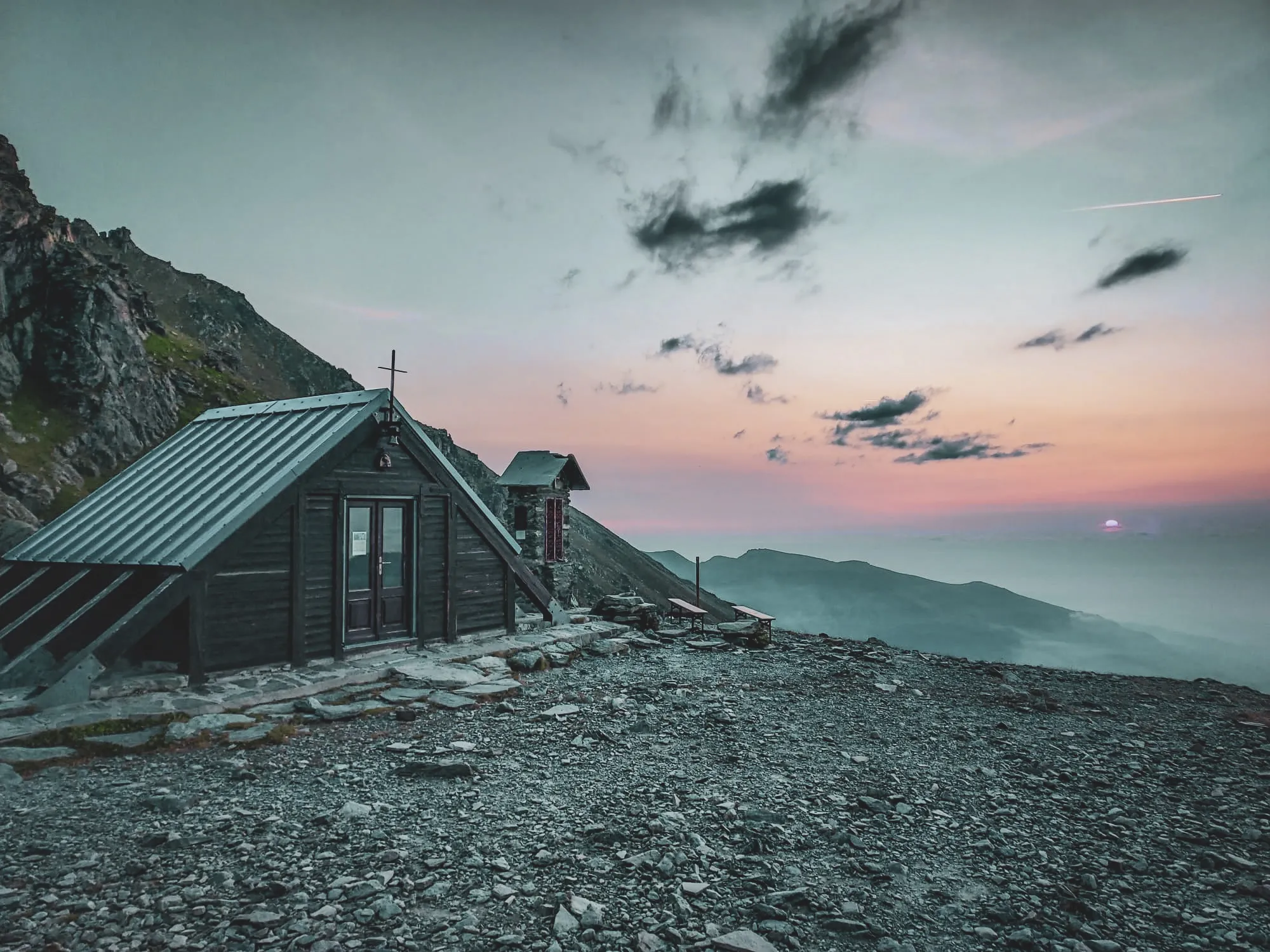 Refuge montagnard au coucher de soleil, entouré de paysages alpins à couper le souffle.