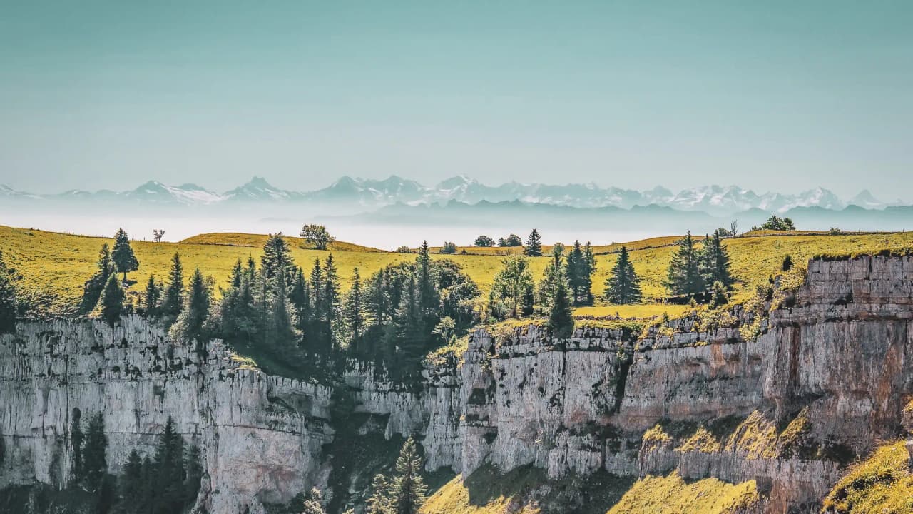 Panorama of the Jura: lush green landscapes, majestic cliffs and distant mountains.