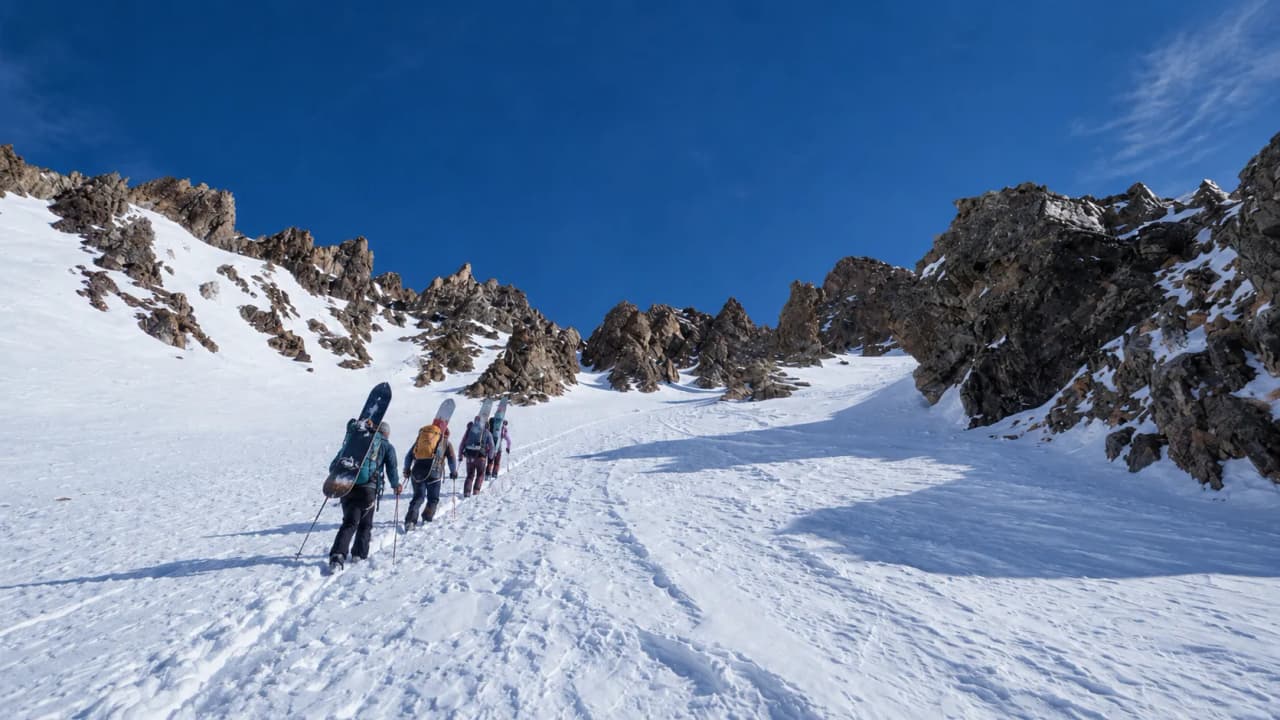 A group of adventurers climbing through pristine snow, heading towards the rocky peaks of the Clarée.
