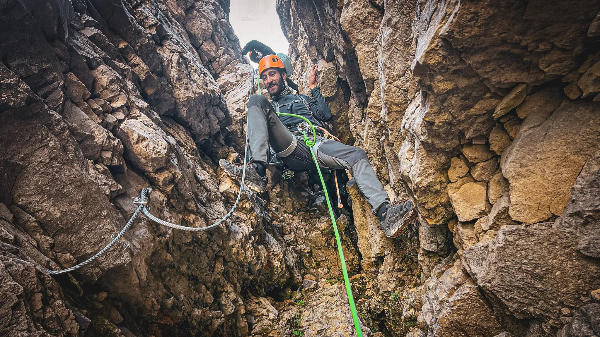 A fully kitted-out climber making his way through a narrow rocky passage on Mont Aiguille, surrounded by spectacular scenery.
