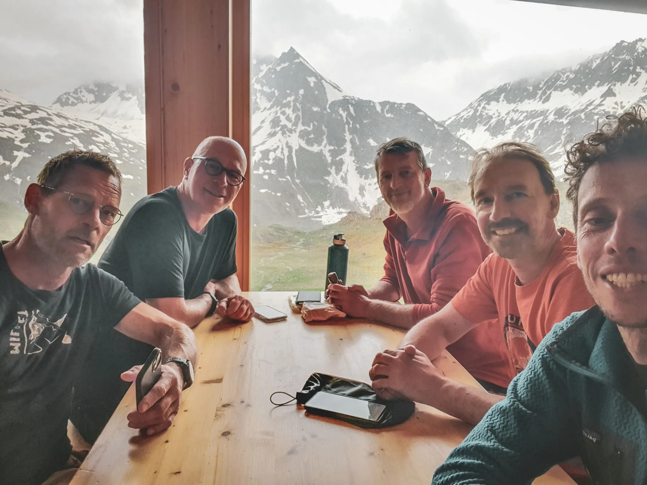 A group of five friends sharing a convivial moment with majestic mountains in the background.