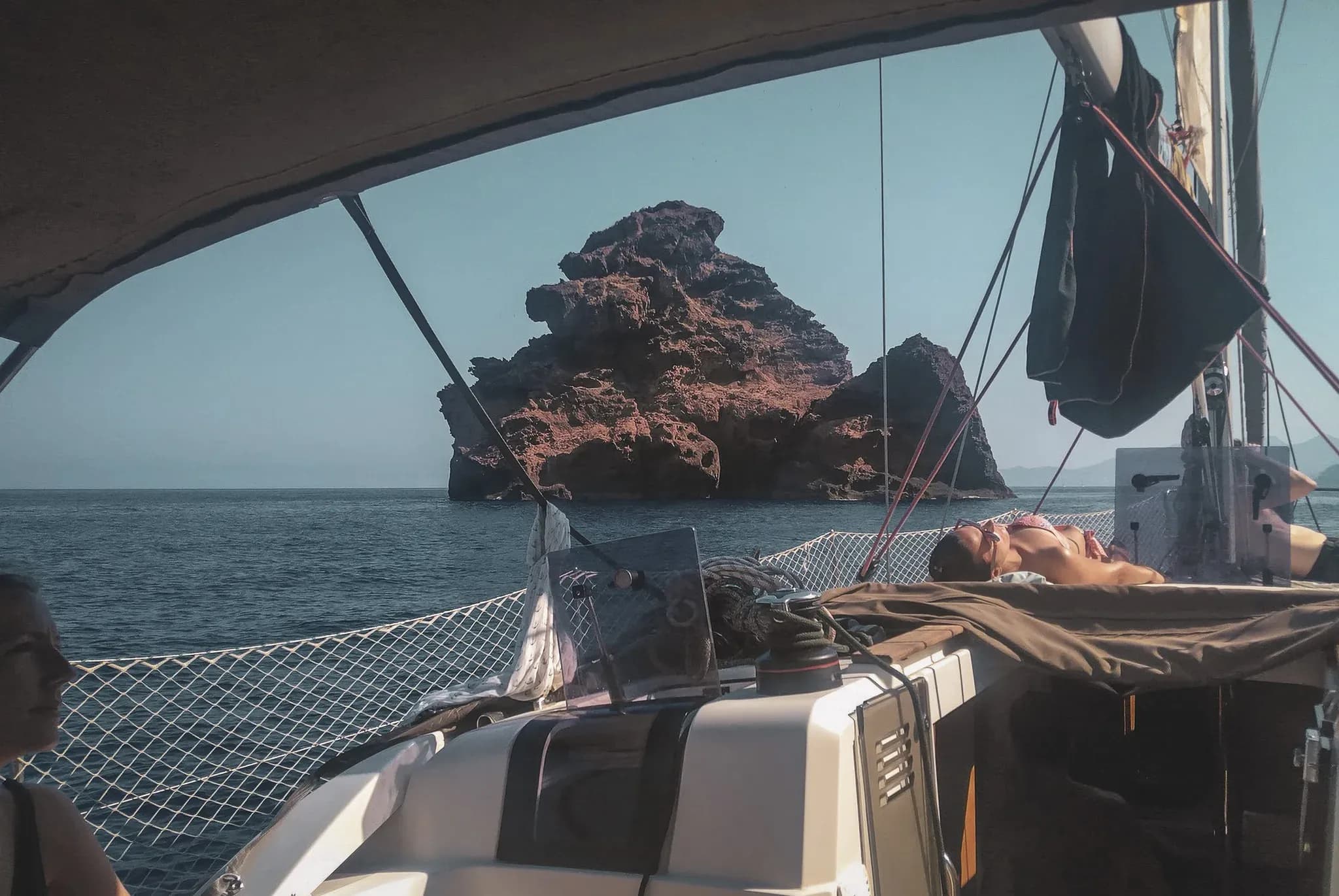 Vue apaisante d'un bateau voguant en mer, avec un rocher impressionnant en arrière-plan.