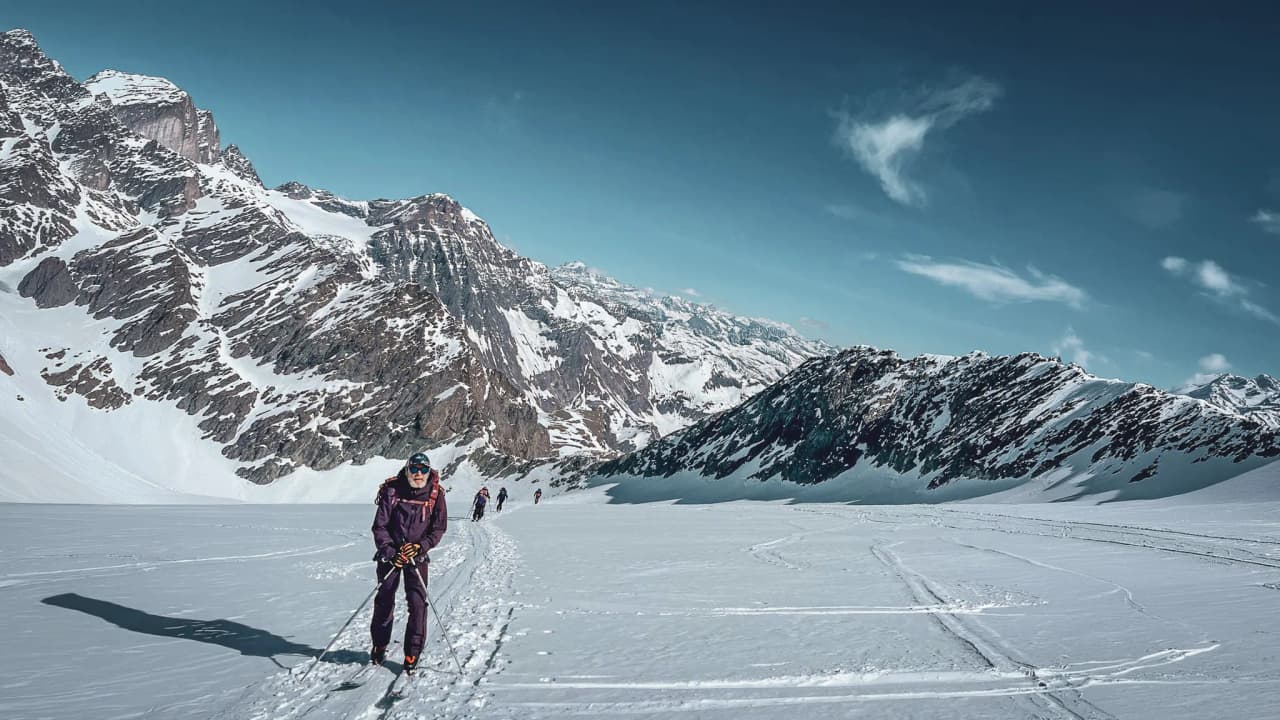 A skier on a majestic glacier, surrounded by snow-capped mountains under a brilliant blue sky.