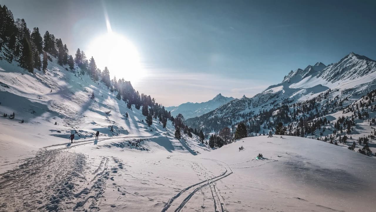 A winter hike through a snow-covered valley, surrounded by majestic mountains.