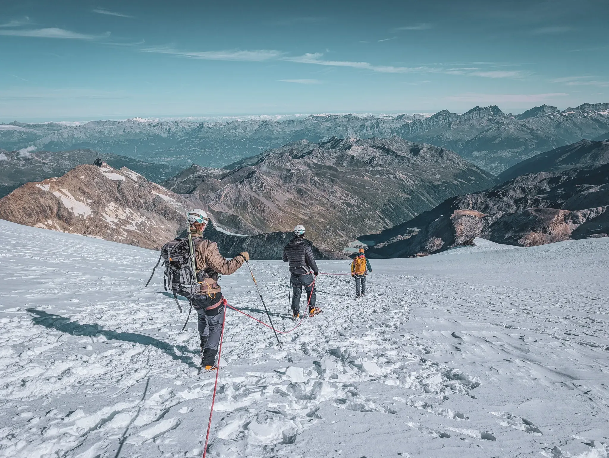 A group of climbers on a glacier, with majestic peaks in the background.