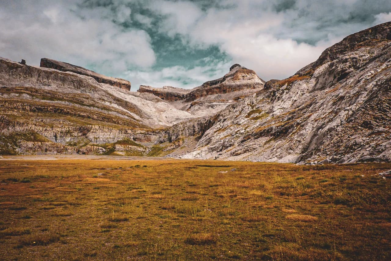 Un vaste cirque montagneux aux parois rocheuses s'élève au-dessus d'une plaine de haute altitude